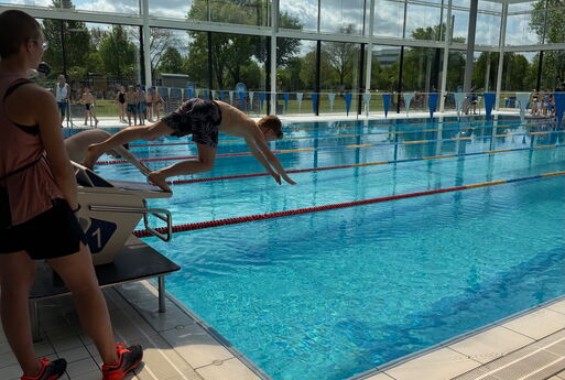 Ein Junge macht einen Startsprung ins Wasser vom Startblock