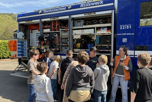 Schüler stehen vor dem Einsatzwagen des THW. Eine Frau erklärt etwas.