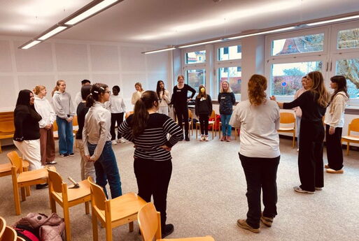 SchülerInnen und 2 Coaches stehen im Kreis