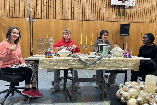 SchülerInnen sitzen an einem gedeckten Tisch und lachen