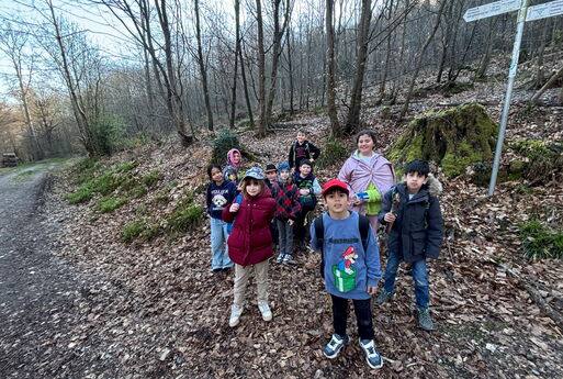 Zehn Jungs und Mädchen stehen in einem Wald und schauen in die Kamera