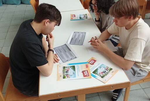 Drei Jungen sitzen an einem Tisch und arbeiten an ihren Aufträgen.