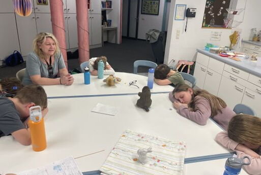 Kinder spielen Werwolf und liegen schlafend auf dem Tisch