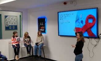 Jugendliche hören einer Lehrerin zu, die etwas auf dem interaktiven Panel präsentiert