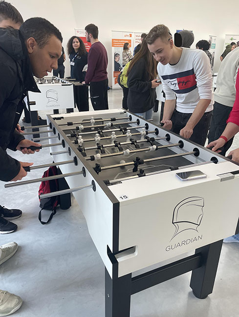 Vier Schüler der Beruflichen Bildung stehen um einen Tischkicker herum und spielen gemeinsam.