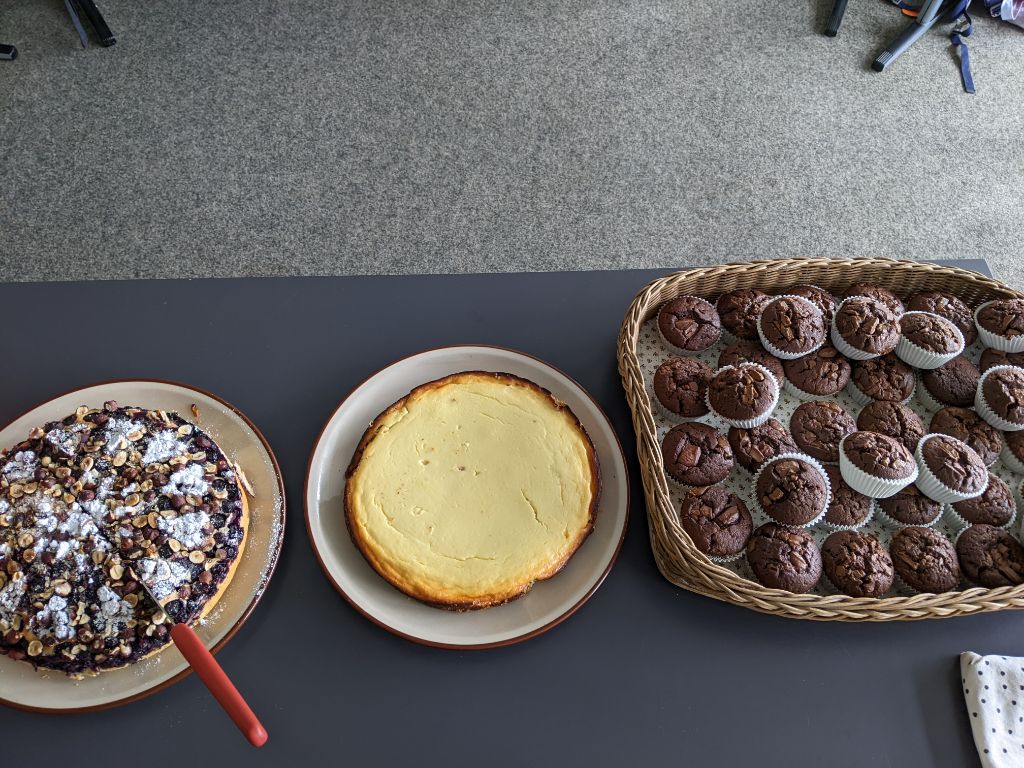 Auf einem Tisch stehen zwei ganze Kuchen und ein Tablett mit Mussins.